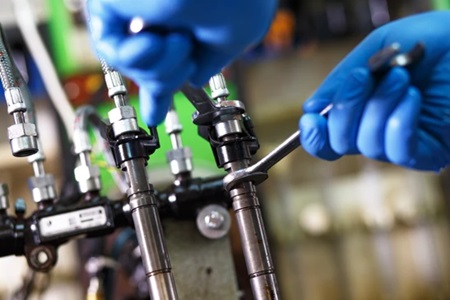 image of nitrile gloved hands using wrenches to open fuel lines